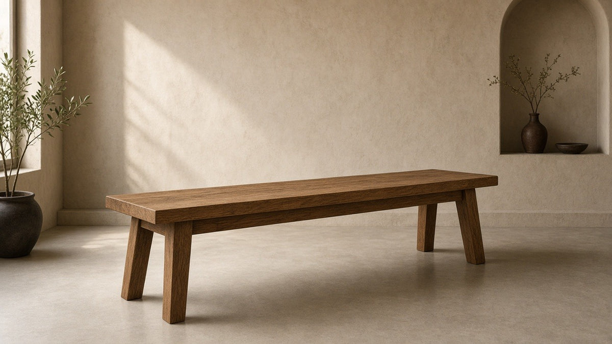 Solid wood bench 60 inches in empty hall, warm plaster walls, soft daylight