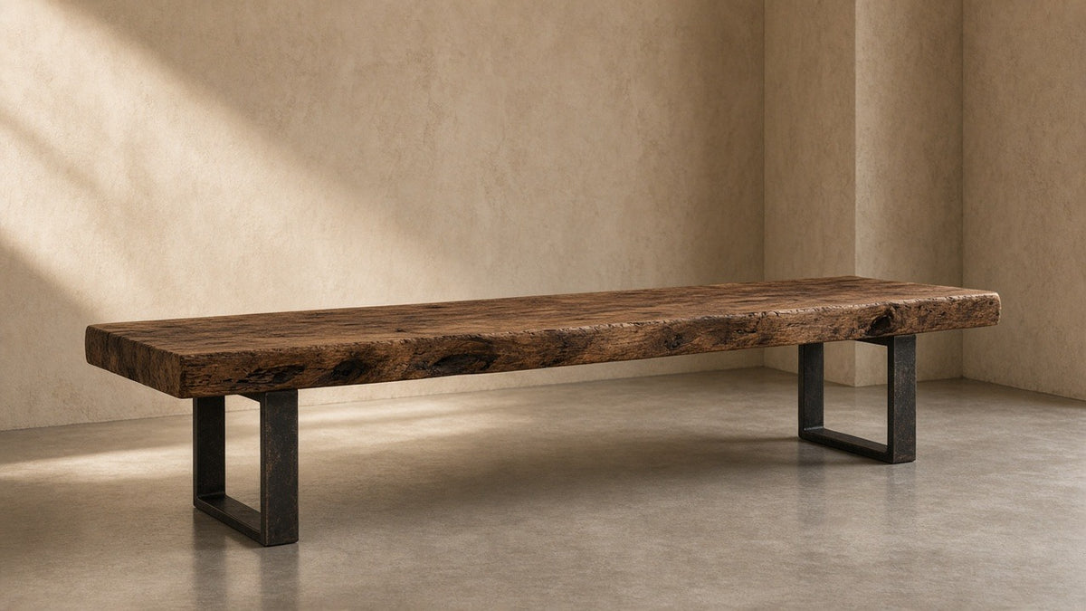 Reclaimed mango wood bench with metal legs in empty hall, warm plaster walls, soft daylight