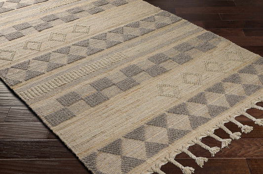 A textured, geometric-patterned rug with tassels on a wooden floor, beige and grey tones.