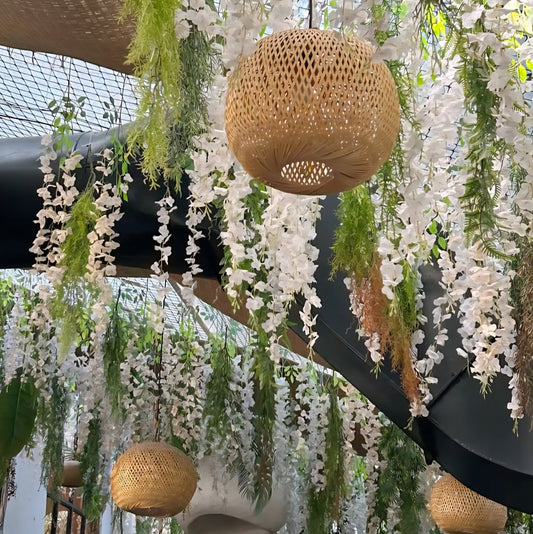 Bamboo pendant lights with woven detailing and dried flower garlands hanging from ceiling with a modern indoor setting