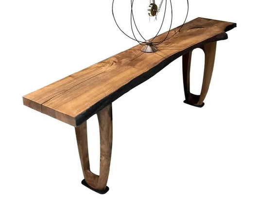 A rustic console or sofa table made of walnut with visible grain and dark stain, simple legs, and a modern wire sculpture on top.