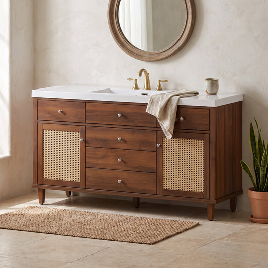 60" wooden bathroom vanity with SMCC sink and wicker inserts, white countertop, brass hardware, beige towel, natural setting, beige wall, wicker floor mat, potted snake plant.