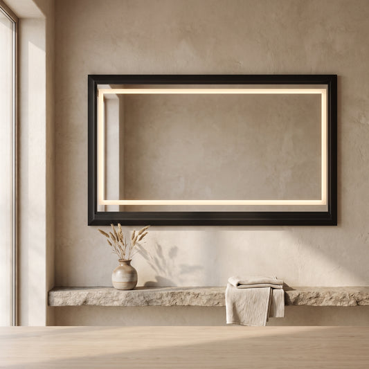 60" Oversized Rectangular Bathroom Mirror with black frame and backlit mirror hanging on wall, accompanied by vase and folded towel on stone ledge, minimalist decor in neutral tones.