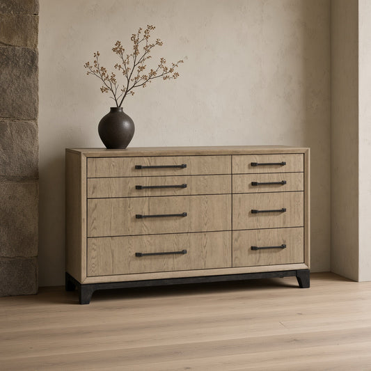 Modern 8 drawer dresser with feet and pulls, light wood finish and metal handles. Black legs. Vase with branches on top. Minimalist room with stone wall and wooden floor.