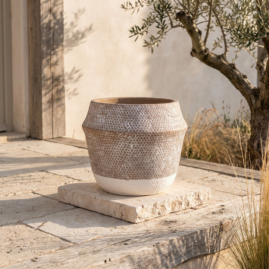 Textured white and beige planter on stone base, outdoors near tree