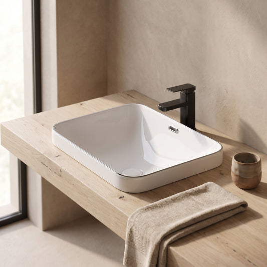 A white ceramic undermount sink 22.05" x 15.36" mounted on a light wood countertop in a minimalistic space with a towel and small cup nearby.