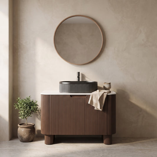 Bathroom vanity with textured brown cabinet, white countertop, and modern sink, with circular mirror and plant decoration.