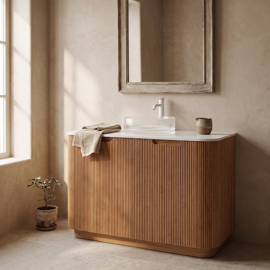 Wooden bathroom vanity with white countertop and basin, framed mirror above, beige walls, potted plant beside, bathroom setting