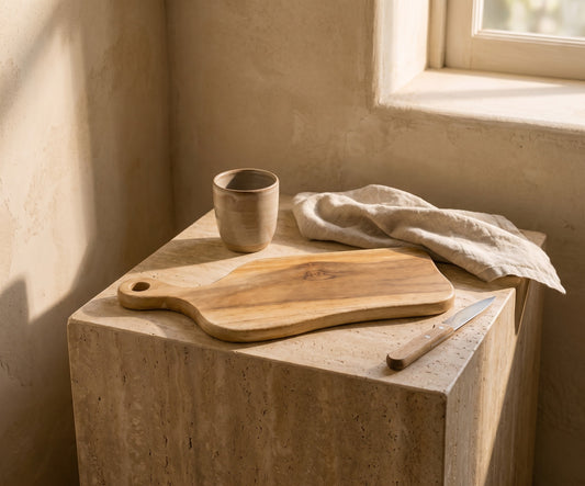 Drift Teak Cutting Board: teak wood, light brown, on a marble pedestal with a ceramic cup and knife background.