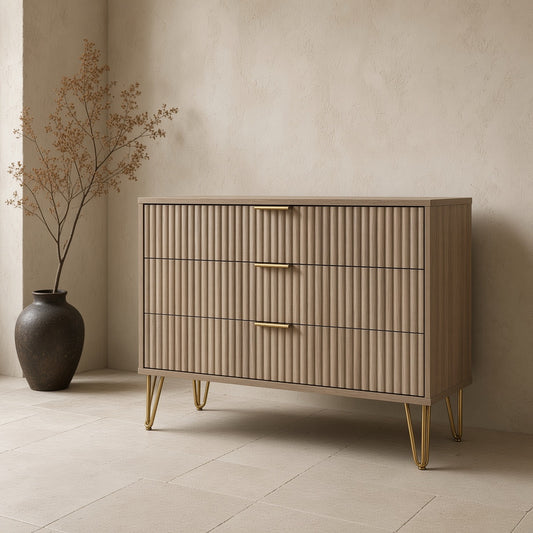 A light wooden fluted dresser with brass handles and legs in a minimalist room setting.