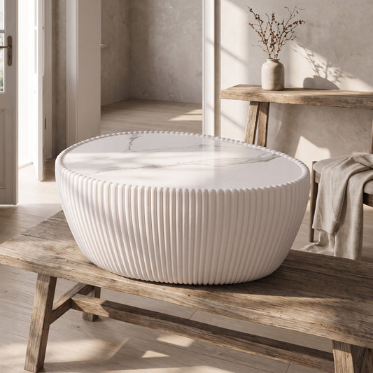 Goose egg-shaped coffee table with sintered stone top, white with marbled pattern, on wooden bench, natural light, minimalistic setting