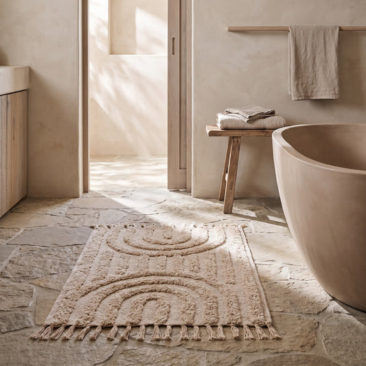Hand-knotted bath mat with tassels, light beige, rustic bathroom with stone floor and wooden fixtures