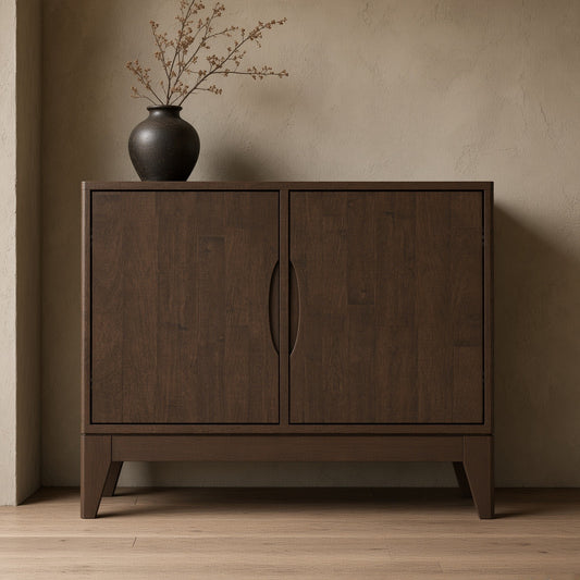 Dark wooden sideboard with two doors and handles, placed against a textured wall. A dark vase with branches is on top. Light brown wooden floor.