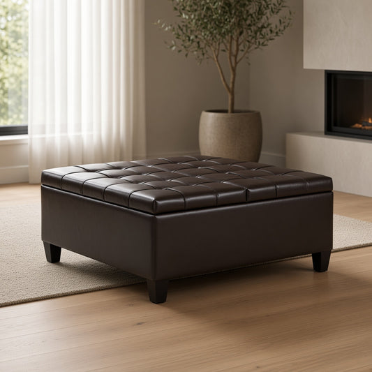Tufted leather ottoman on a wooden floor with a plant and fireplace in the background