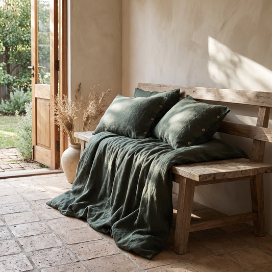 Forest Green Linen Duvet Cover Set on rustic wooden bench, open door to garden in background.