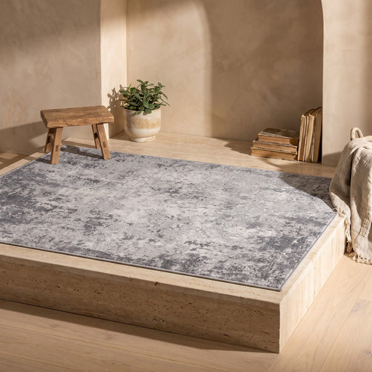 Abstract rug with grey and white pattern on a wooden platform under sunlight