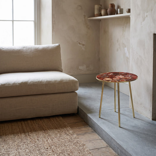 Maroon red agate round coffee/side table on brass legs in a living room setting.