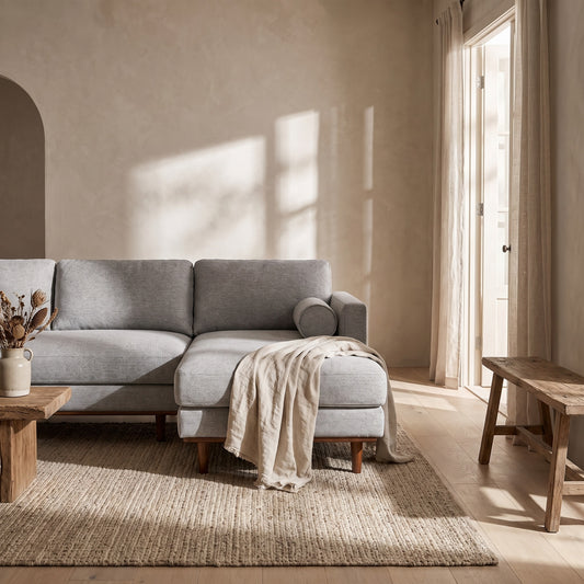 A grey Morrison Right Sectional Sofa with a white throw, small wood table, and beige rug. Natural light illuminates the room.