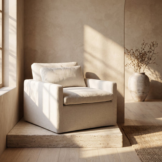 Beige swivel chair with a toss pillow on a natural stone platform near a window with soft sunlight, minimal decor background
