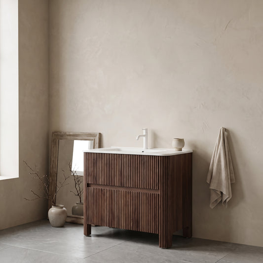 Bathroom vanity with a striped walnut finish, white sink, and modern faucet in a minimalist setting with beige walls and gray floors, accompanied by a towel and a vase.