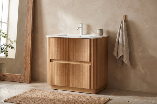Natural wood vanity with 30-inch sink, featuring a soft beige wall, large mirror, and simple beige mat