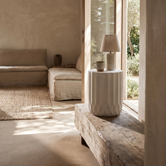 Outdoor end table with scallop edge, antique white finish on wooden bench, living room backdrop.