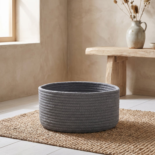 Gray jute round organizer basket on woven mat by window