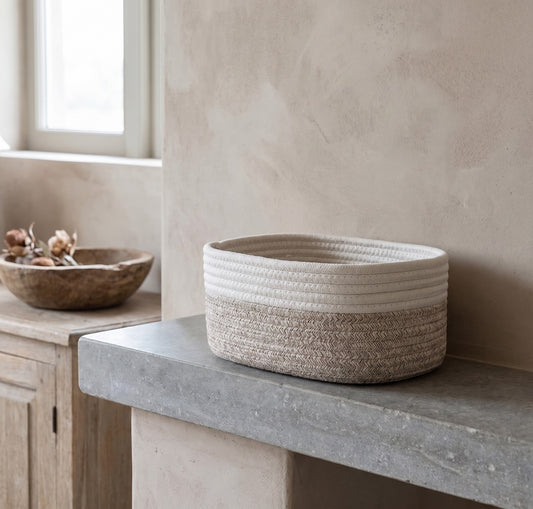 Beige woven jute rope basket on a concrete counter in a minimalistic setting