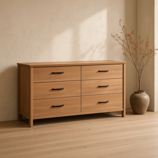 A six-drawer dresser made of light brown solid wood, displayed in a room with a light wooden floor and a tan wall.