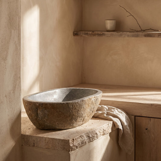 Natural stone basin on wooden shelf in a serene setting with neutral tones and sunlight effect.