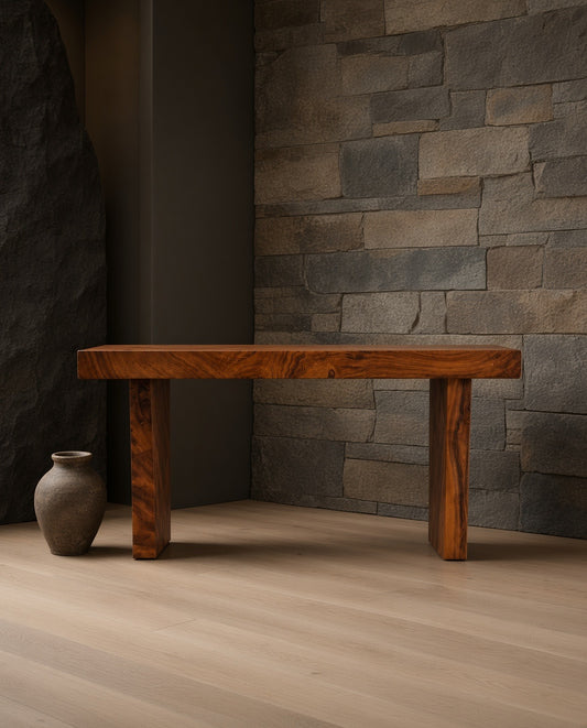 Rectangular wooden console table with natural grain, placed in front of stone wall and a large gray rock, with a terracotta pot to the left.