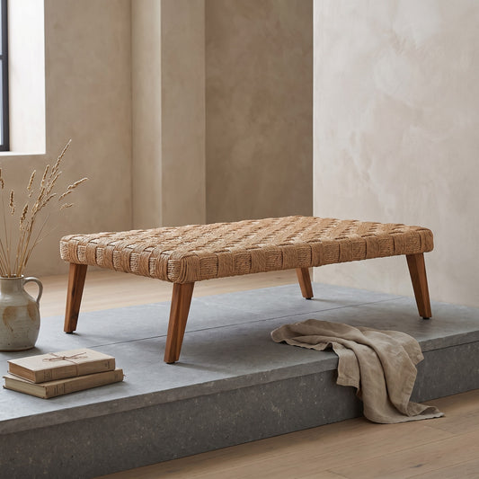 A wicker bench with wooden legs on a concrete platform.