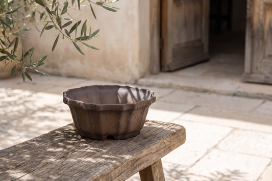Textured clay pot on wooden bench, outdoors