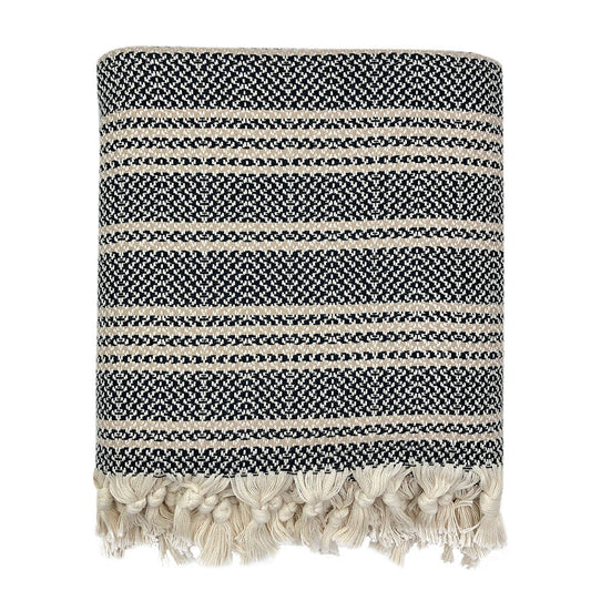 A woven stripe Turkish throw with navy and beige stripes and tassels at the bottom, viewed against a white background.