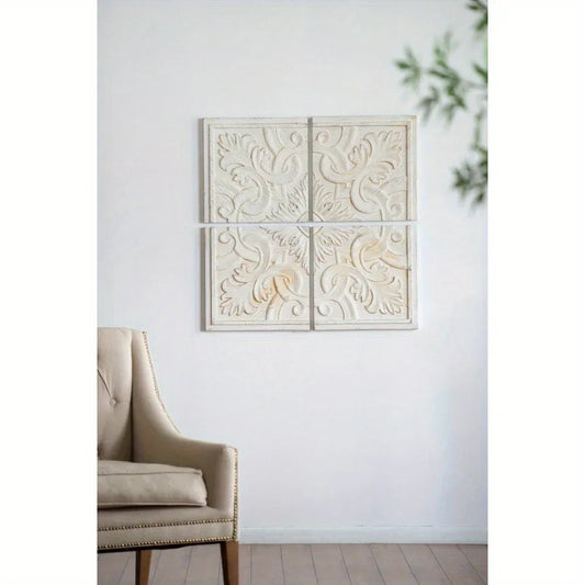 Four square wall decorations with intricate white designs mounted in a grid pattern, shown in a minimalist setting with a beige armchair and green leaves in the corner.