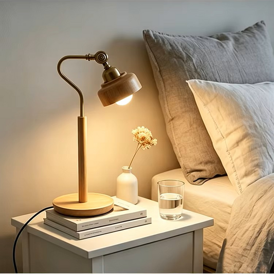Modern wood and brass desk lamp on a bedside table with a nightstand lamp setup with a bed in the background