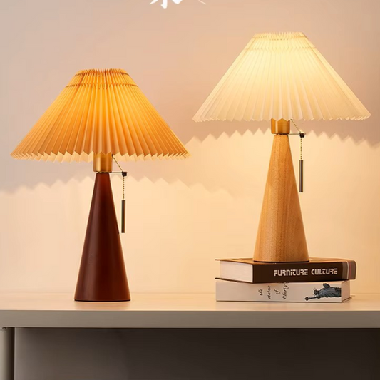 Two table lamps with pleated shades, one dark brown and the other light wood, sitting on books, soft lighting background